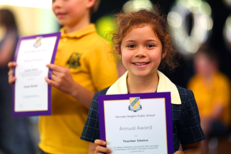 Two students proudly holding up their certificates that acknowledge their efforts in class.