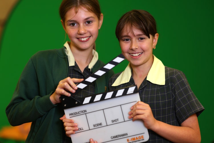 Two media team girls holding clapperboard.