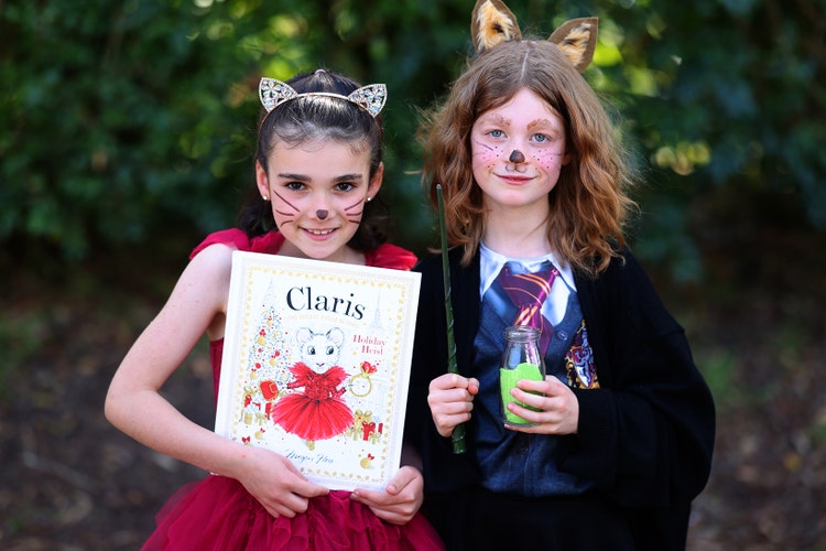 Two girls dressed up for book parade. One is dressed as a mouse in a red dress and the other is dressed as a cat in a black gown.